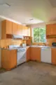 kitchen with orange backsplash tile, concrete floors and wood cabinetry in 1946 Albert Frey designed home
